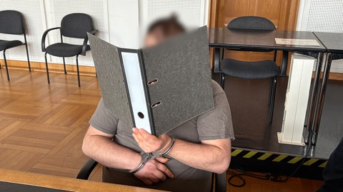 Der Angeklagte, der seine damalige Freundin vergewaltigt haben soll, verbirgt sein Gesicht.