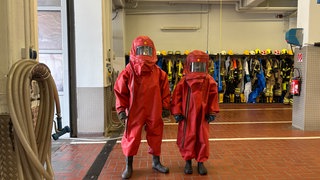Zwei Azubis der Werkfeuerwehr BASF im roten Schutzanzug