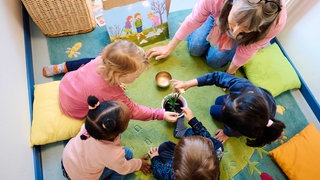 Kindergartengruppe beim Spielen mit Erzieherin 