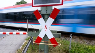 Ein Zug fährt über einen Bahnübergang (Symbolbild). Neben dem Bahnhof in Jockgrim hat es am Montagmorgen einen schweren Unfall gegeben. Ein Fahrradfahrer wollte trotz geschlossener Schranken den Bahnübergang überqueren – und wurde von einer Lok erfasst. 