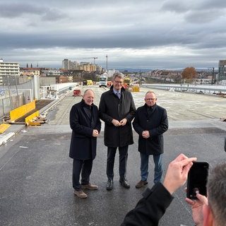 Bundesverkehrsminister Patrick Schnieder steht mit Vertretern aus Ludwigshafen auf der Baustelle einer Hochstraße.