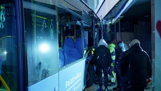 Bus in Neustadt ist in Hauswand gekracht, Rettungskräfte und Helfer neben dem zerstörten Bus