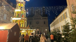 Bereits seit April ist die Außenbeleuchtung des Speyerer Dom abgeschaltet. Zurzeit fällt das besonders auf. Denn der Weihnachtsmarkt davor ist festlich beleuchtet.