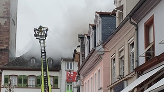 Ein Feuerwehrmann in einem Korb bei einem Brand in einem Speyerer Modehaus. Die Polizei schätzt den Schaden auf mindestens 500.000 Euro.