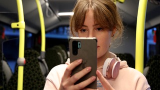 Eine Frau steht mit ihrem Handy in einem Bus. Die RNV hat eine Aktion gegen Handy-Lärm in Bus und Bahn gestartet.
