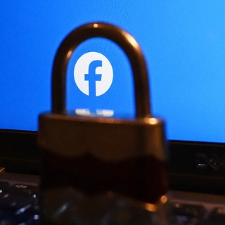 Nahaufnahme durch ein Schloss auf einen Laptop-Bildschirm, auf dem das Facebook-Logo zu sehen ist.  Landau sperrt die Kommentarfunktion auf seiner Facebookseite