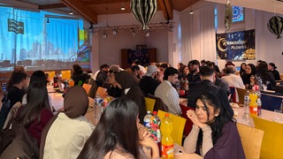 Das Bild zeigt Studierende beim Abendmahl Iftar in einer Kirche in Ludwigshafen. Dort haben sie das Fastenbrechen gefeiert.