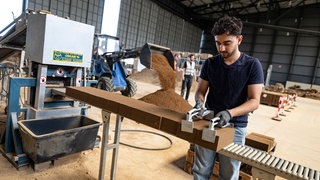 Das Bild zeigt einen jungen Mann bei der Arbeit bei einem Lehmsteinhersteller. Immer mehr junge Menschen in der Pfalz wollen Handwerker werden.