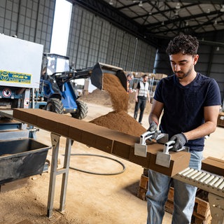 Das Bild zeigt einen jungen Mann bei der Arbeit bei einem Lehmsteinhersteller. Immer mehr junge Menschen in der Pfalz wollen Handwerker werden.