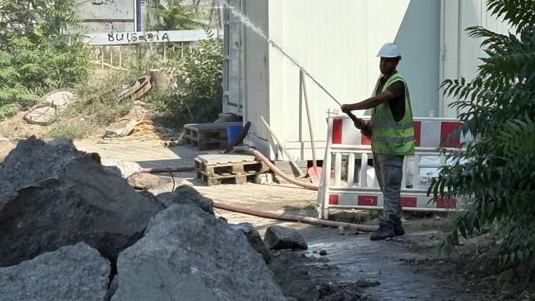 ....um die Anwohner vor Staub zu schützen, spritzt ein Arbeiter Wasser auf den Meißel, der den Beton zerkleinert - so soll weniger Staub entstehen. 