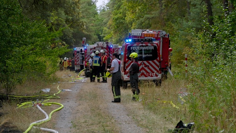 Feuerwehrfahrzeuge auf einem Waldweg. Der Einsatz war laut der Polizei schwierig, denn das Löschwasser musste erst aufwändig über die nahe A61 transportiert werden.