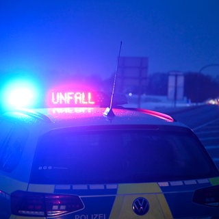Ein Funkstreifenwagen der Polizei weist auf einen Verkehrsunfall hin und sperrt die Straße.