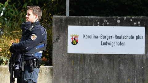Ein Polizist steht vor der Karolina-Burger-Realschule in Ludwigshafen. Herrscht auch an anderen Schulen in der Stadt ein Klima der Angst?