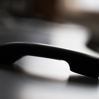 Illustration: Ein abgelegter Telefonhörer. Oft stecken Gruppen oder Netzwerke hinter Telefonbetrug. In Minfeld im Kreis Germersheim ist eine Rentnerin Opfer eines sogenannten Schockanrufs geworden. Laut Polizei erbeuteten die Täter Bargeld und Gold im Wert von 90.000 Euro.