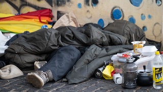 Ein Wohnungsloser liegt in einem Schlafsack.
