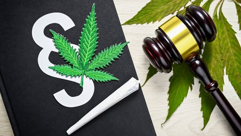 Ein Richterhammer liegt neben einem Joint und einem Maruhuana-Blatt. In Mainz stehte ein Mann wegen Mariuhana-Handels vor Gericht. Sein Fall wird wegen neuer Gesetzeslage noch einmal neu verhandelt. 