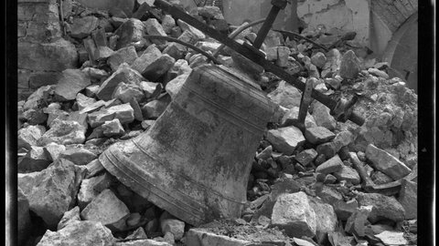Eine Glocke liegt auf einem Trümmerfeld