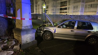 Ein beschädigtes Auto steht vor einer Mauer.