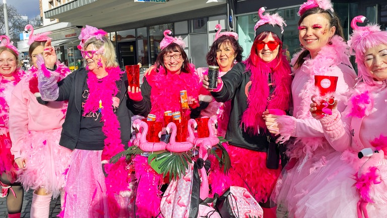 Acht Frauen aus Altrip haben sich rosa- und pinkfarbene Sachen angezogen. Auf dem Kopf haben sie kleine Flamingos. 