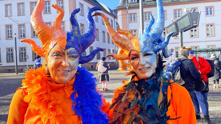Zwei Frauen haben sich an Weiberfastnacht als Feuer und Eis verkleidet. Farblich sind die halb rot und halb blau gekleidet. 
