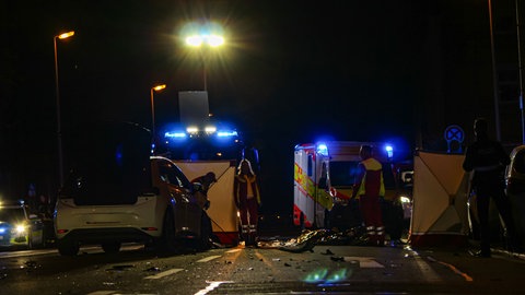 Das kaputte Unfallauto steht auf der Kreuzung in der Nähe eines Mainzer Hotels. Rettungskräfte sind im Einsatz.