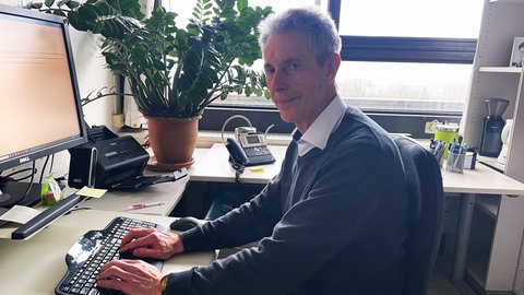 Professor Bodo Plachter von der Universitätsmedizin Mainz sitzt an seinem Schreibtisch in seinem Büro im Institut für Virologie. 