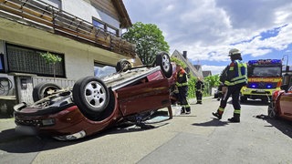 Nach einem Unfall liegt ein Auto in Ingelheim auf einer Straße auf dem Dach. 
