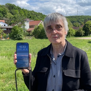 Die Ortsbürgermeisterin von Tiefenthal im Kreis Bad Kreuznach zeigt, dass sie auf der Landstraße keinen Empfang auf ihrem Handy hat.