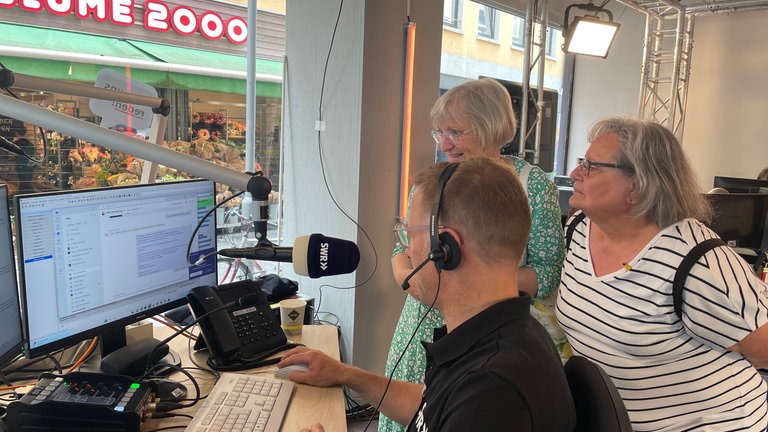 SWR-Nachrichtenredakteur Golo Schlenk erläutert zwei Hörerinnen seine Arbeit. 