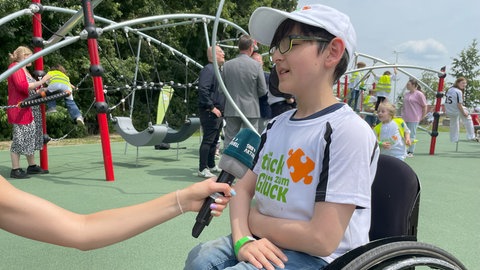 Der zehnjährige Metin wird interviewt und erzählt, dass er sich sehr freut, dass es endlich einen Spielplatz ohne Hindernisse für Rollstuhlfahrer gibt. 