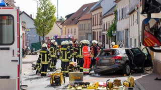 Mehrere Feuerwehrleute stehen an der Unfallstelle in Udenheim in Rheinhessen.