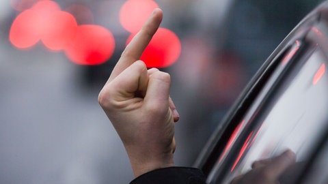 Einen sogenannten "Stinkefinger" zeigt ein Autofahrer aus seinem Auto.