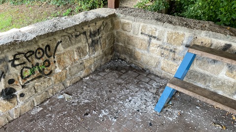 In einer Ecke der Grillhütte in Stadtecken-Elsheim liegt ein Häufchen Asche. An der Wand ist ein Graffiti-Schriftzug