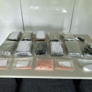 Tabletten, Waffen und abgepackte Drogen liegen auf einem Tisch: Drogen im Wert von einer Million Euro hat die Polizei in einer Lagerhalle in Worms gefunden. 