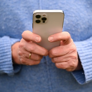 Eine Frau hält ihr Handy mit beiden Händen. Eine 50-Jährige ist in Bad Kreuznach Opfer von Love Scamming geworden.