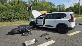 Ein Motorrad liegt vor einem Auto, nachdem es mit ihm zusammengeprallt ist.