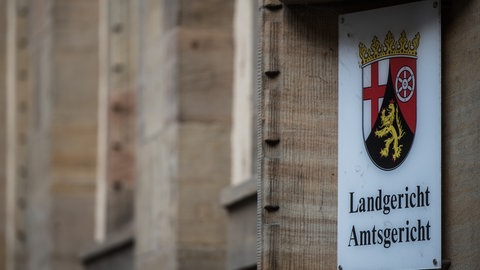 Ein Schild mit dem Landeswappen an der Fassade des Mainzer Landgerichts. Am Freitag beginnt der Prozess gegen einen 16-Jährigen mutmaßlichen Islamisten aus Bingen. 