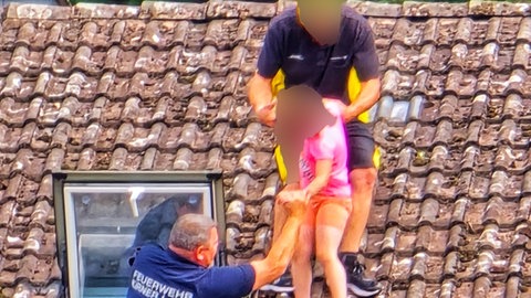 Ein Feuerwehrmann nimmt das kleine Mädchen in Empfang - der Vater hat die Kleine auf dem Dach selbst gerettet.