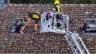 Erleichterung: Der Vater kann seinen kleinen Sohn dem Feuerwehrmann in der Dachluke übergeben.