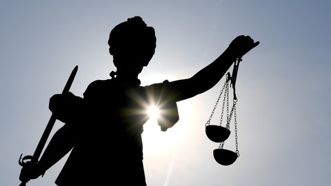 Die Göttin Justitia im Gegenlicht an einem Brunnen. Am Landgericht Bad Kreuznach wurde ein Arzt verurteilt. 