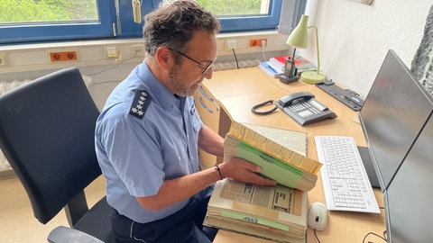 Der Mainzer Polizeisprecher Rinaldo Roberto blättert im polizeieigenen Zeitungsarchiv. Artikel aus dem vergangenen Jahrhundert zeigen: Konflikte im Straßenverkehr sind auch in Mainz nichts Neues. 