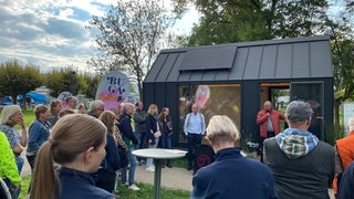 Vor dem Buga-Mobil haben sich viele Menschen versammelt.