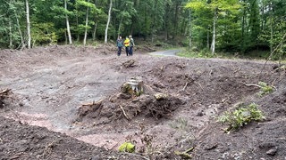 Revierleiter Tobias Helfenstein (links) vor einer Mulde, die künftig bei Starkregen das Wasser im Wald bei Kirn-Sulzbach auffangen soll. 