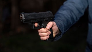 Eine Person hält eine Schusswaffe in der Hand.