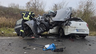 Ein völlig zerstörtes Auto hängt halb auf einem anderen Wagen. Bei dem Frontalzusammenstoß bei Erbes-Büdesheim wurden drei Menschen schwer verletzt