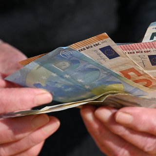Geldscheine in der Hand eines Senioren. Der Betrüger wollte 240.000 Euro in bar mitnehmen. 