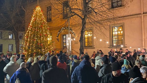 Viele Menschen stehen um den geschmückten, neuen Weihnachtsbaum in Gimbsheim herum.
