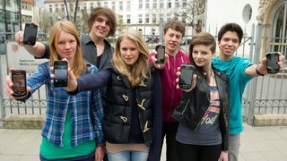 Eine Gruppe Jugendliche hält ihre Smartphones ins Bild