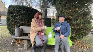 Gemeindeschwester Plus, Heike Lörcher-Denne, sitzt mit Erwin Bernhardt auf der Plauderbank. 
