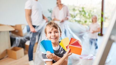 Familie zieht in neue Wohnung ein - Junge mit Farbkarte